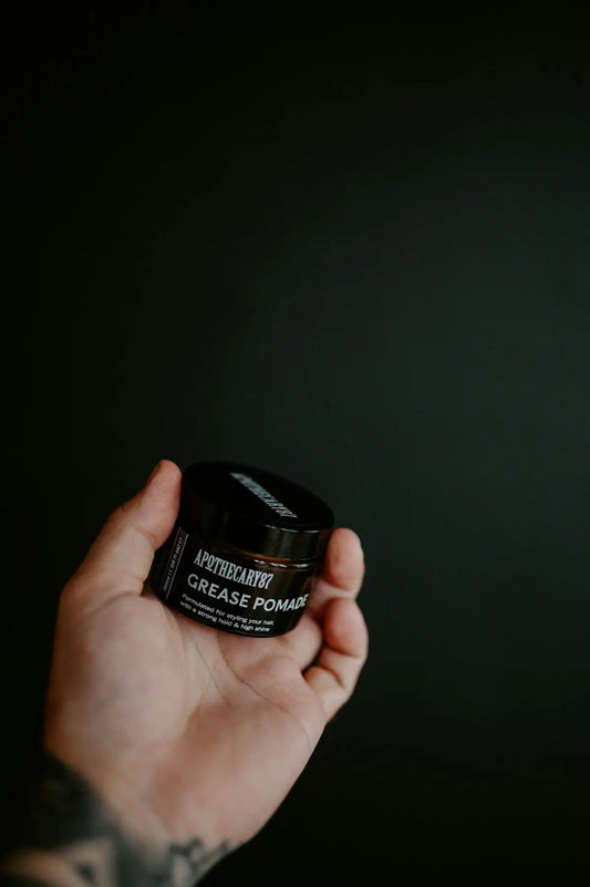 Hand holding a jar of grease pomade