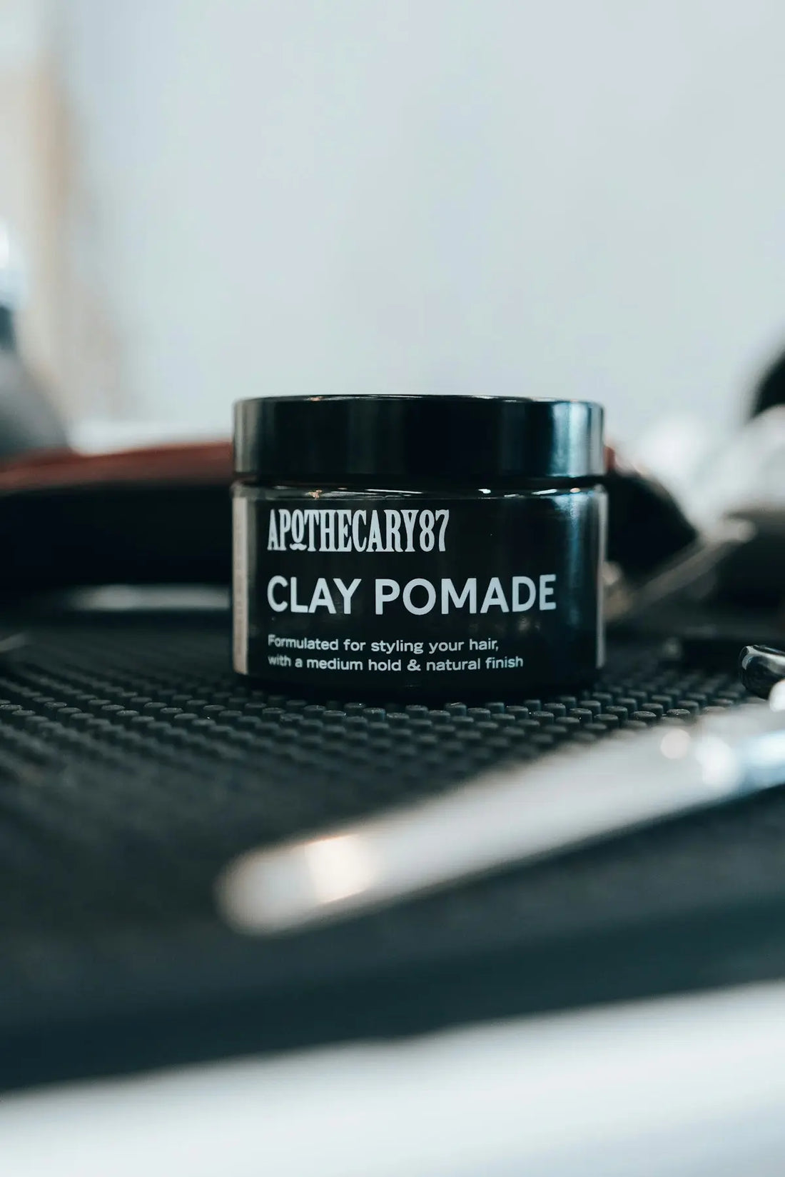 A jar of apothecary87 clay pomade for styling hair.
